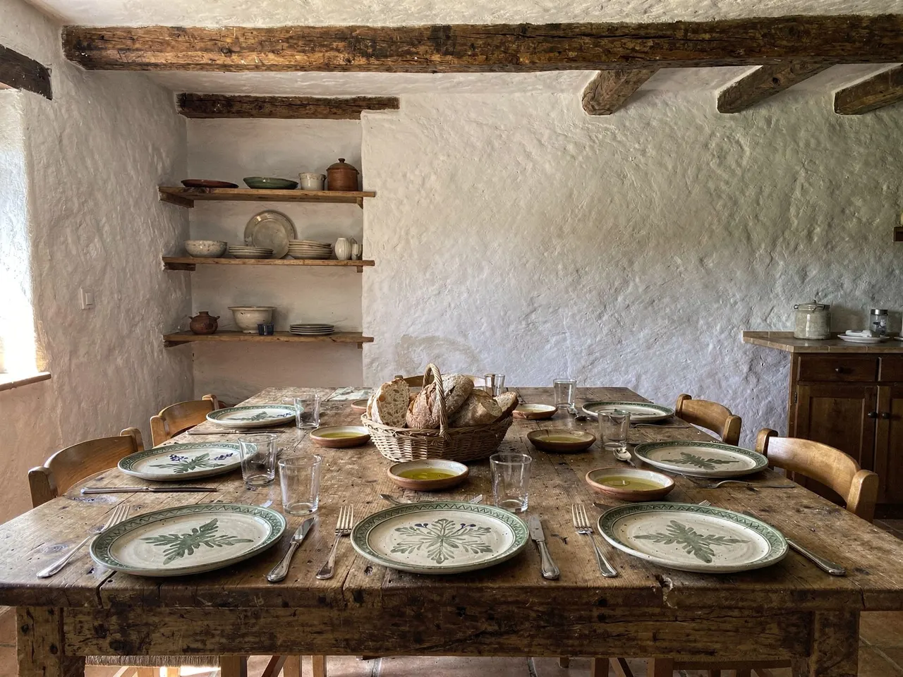 Mesa rústica del comedor puesta para el grupo, con pan y aceite